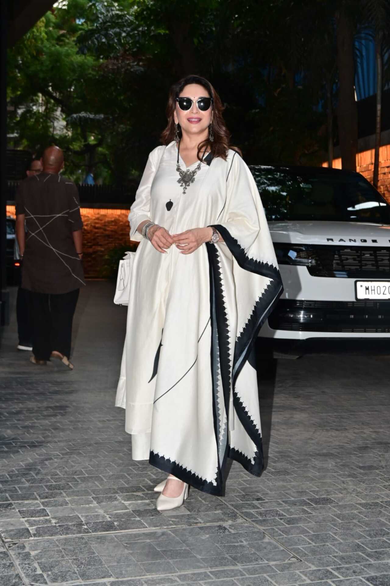 Madhuri Dixit makes a striking statement in an elegant ivory white kaftan-style silhouette, beautifully framed by a bold black scalloped border.